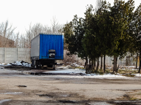 a cargo trailer stands next to the trees, spring the snow meltsの写真素材