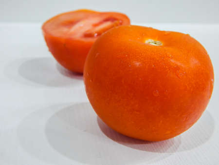 fresh tomatoes with water drops, whole and wedgeの写真素材