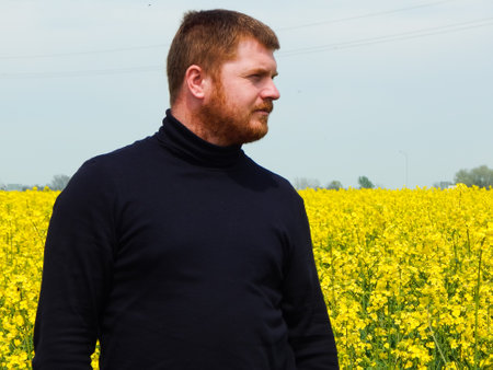 a man stands in a blooming yellow rapeseed fieldの写真素材