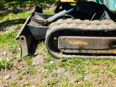 An old excavator stands on the grass in the park on a sunny day.の写真素材
