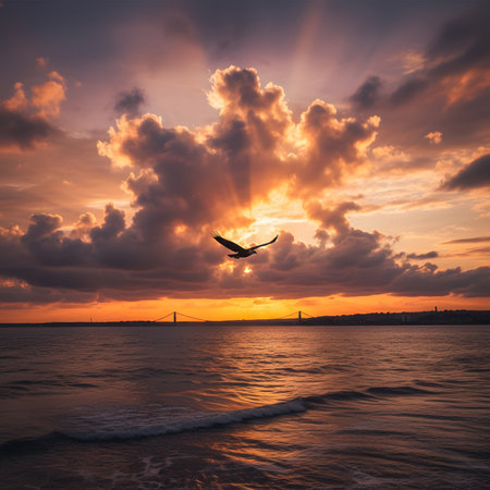 Bird silhouette at radiant sunset over ocean, waves, and distant city bridge.の素材