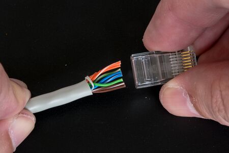 Fitting an RJ45 plug to the end of an Ethernet cable.