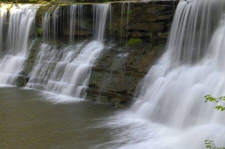 Water cascades over a rock wall into a lagoon below. Horizontal shot.の写真素材