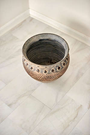 Large grey, clay vase in natural light on white carpeting/tileの写真素材