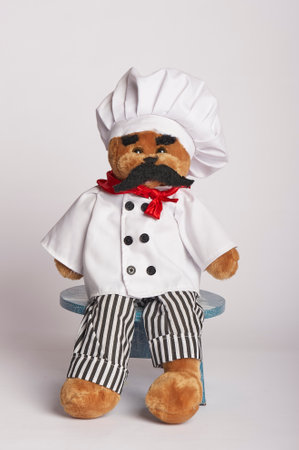 stuffed bear dressed as chef with white jacket and toque. red bandana around neck. black full mustacheの写真素材
