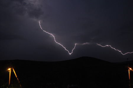 Dark picture of a powerful lightning in the night sky. Rainy autumn day