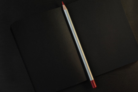 Red pencil for drawing on the dark black notepad. Office creativity equipmentの写真素材