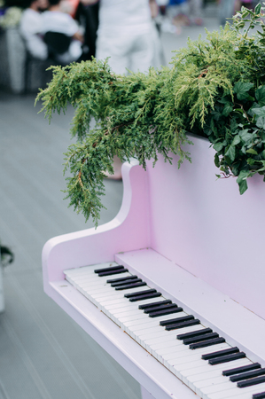 Pink retro piano decorated with green flora outdoorsの写真素材