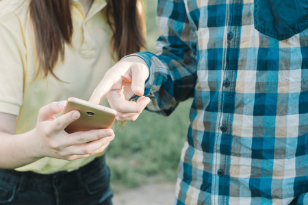 Teenager touching a screen of a smartphone. Students watching at mobile phone. Technologyの写真素材