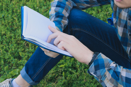 Student watching at a notebook. Teenager sitting outdoors and studying