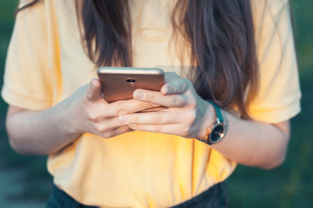 Smartphone closeup in womans hands. Teenage girl holding a phone. Woman touching a screenの写真素材