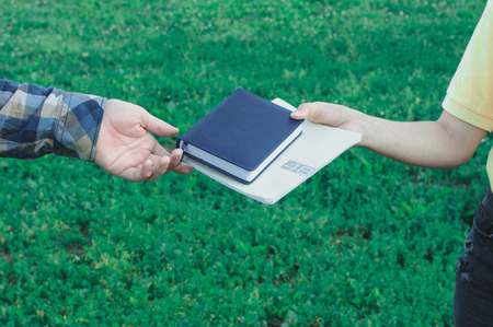 Boy returning books to girl outdoors near college. Students learningの写真素材