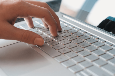 Man's hand on the laptop keyboard close-up. Typing a messageの写真素材