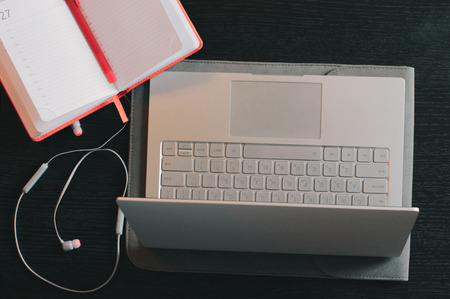 Top view of the opened laptop, notebook with pen and headphones on the wooden deskの写真素材