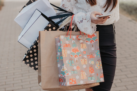 Woman using a mobile phone with shopping bags in hands. Fashionable packagesの写真素材