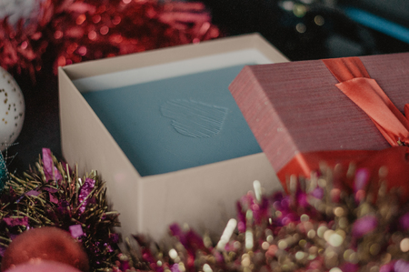 Open christmas box with garland and balls on the wooden table. Gift packaging in macro
