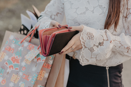 Woman with shopping bags holding a leather wallet. Concept of epmty purse after black friday saleの写真素材