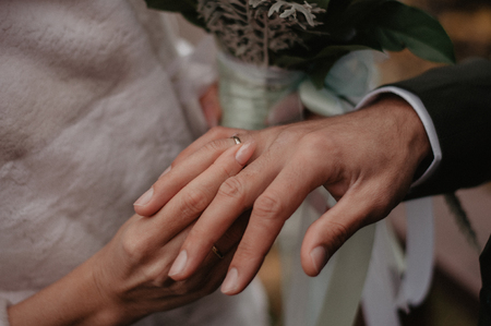 Bride wears gold wedding ring on the groom's finger. Marriage closeupの写真素材