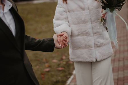 Bride and groom holding hands after wedding ceremony. Woman with wedding bouquetの写真素材