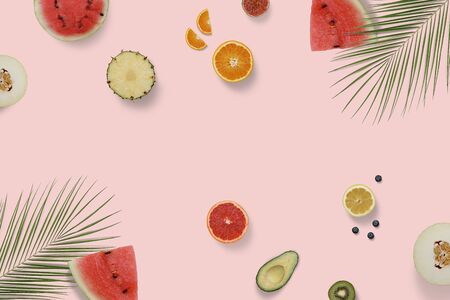 Summer exotic fruit top view flatlay with green palm leaves. Sliced watermelon, avocado, kiwi,...