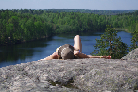 young woman relaxing on the top of a cliff above the lake Yastrebinoye,  Priozersky district, Leningrad region, Russiaの写真素材