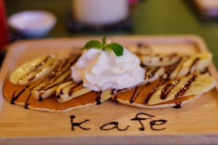 crepes with banana and chocolate cream on wooden plateの写真素材
