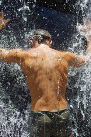a man taking a relaxing shower under a waterfall outsideの写真素材