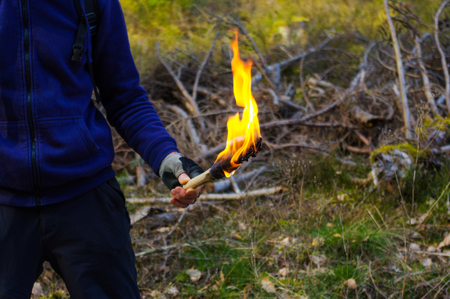 Man hand with torch and flame in wild nature background.の写真素材