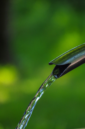 Close up of running water from a tap on green backgroundの写真素材