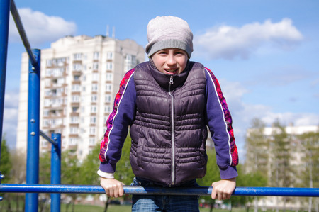 Young athletic girl hanging on horizontal bar