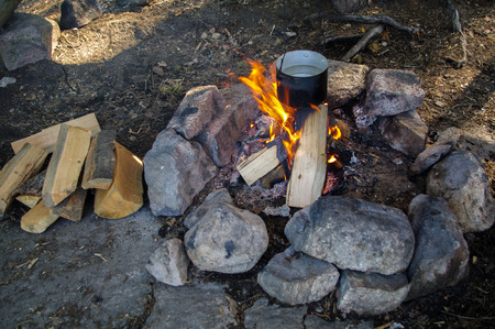 Preparing food on campfire in pot, wild campingの写真素材
