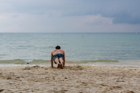 Workout Exercise. Handsome Active Man With Fit Muscular Body Doing Push Ups Exercises. Sporty Athletic Male Exercising At Beach, Training Outdoor. Sports And Fitness Conceptの写真素材