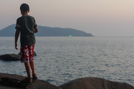 Young boy on Beach Summer Vacation, Guy Standing Back Seaside Blue Water Sea Ocean Holiday Travelの写真素材