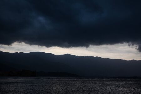 black dramatic clouds over the mountains and the sea