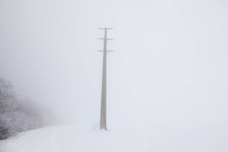 electric pole on a snowy hillの写真素材