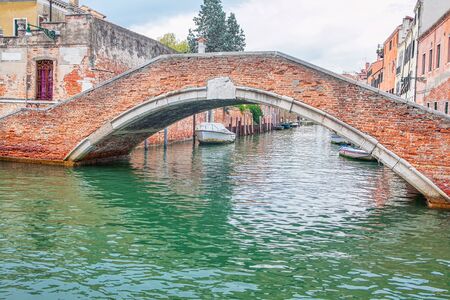 old red bricks bridge and water canal in Veniceの写真素材