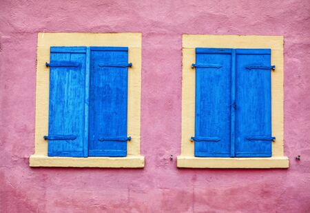 pink wall with wooden blue windowsの写真素材