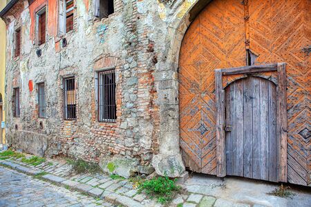 old house with big wooden gate and broken wallの写真素材