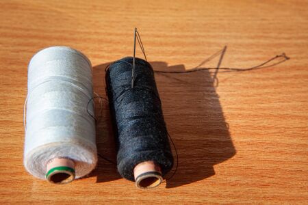 white and black thread with sewing needle