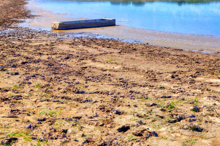 Wooden fishing boat at the dirty river shore