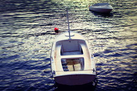 Empty boats in the twilight . Two moored white boats