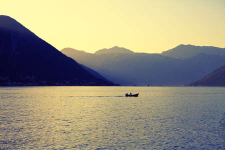 Calm morning on the bay with dawn . Fishing boat on the lagoon surrounded by mountains . Spectacular...