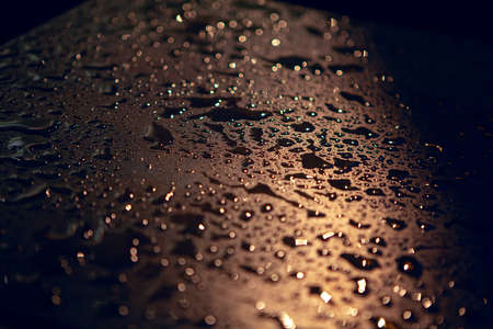 Rain drops on the illuminated surface . Night pluvial texture