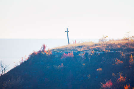 Wooden cross on the autumn hill . Christianity symbol on the top