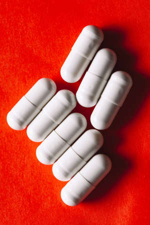Pills in white capsules at red . Pills for the treatment of stomach diseasesの写真素材