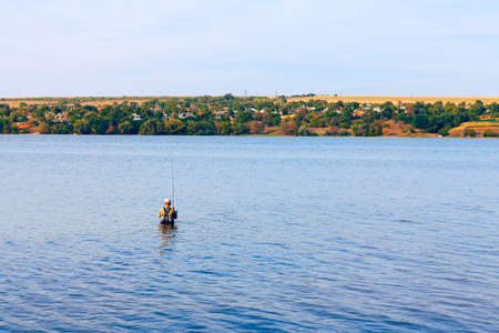 Man standing in water and fishing . Guy fishing in the river . Leisure activity