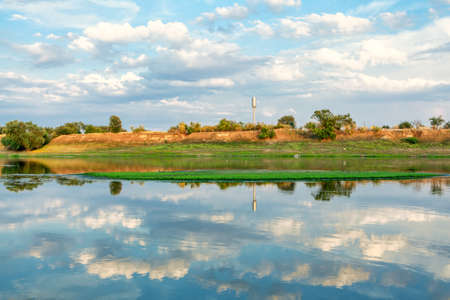 Clouds reflection in the river water . Rustic riverside landscape