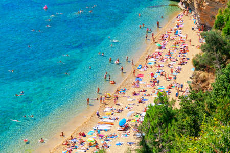 Crowd of people resting on the sandy beach . Aerial view of seaside with tourists . Famous Mogren Beach in Budva Montenegroのeditorial素材