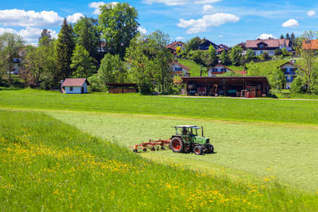 Village farmland . Agriculture farming field with tractor . Green countryside in the springtime . Typical village in Germanyの写真素材