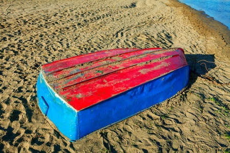 Upside down boat on the beach . Boat colored in red and blueの写真素材